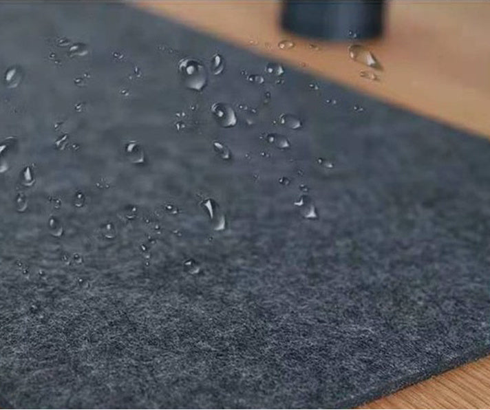 Dark gray wool pad with water droplets on a wooden background